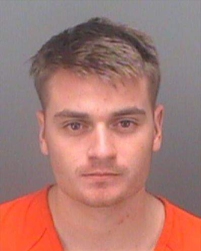 a headshot of a white man with light brown/blond hair in an orange shirt. 