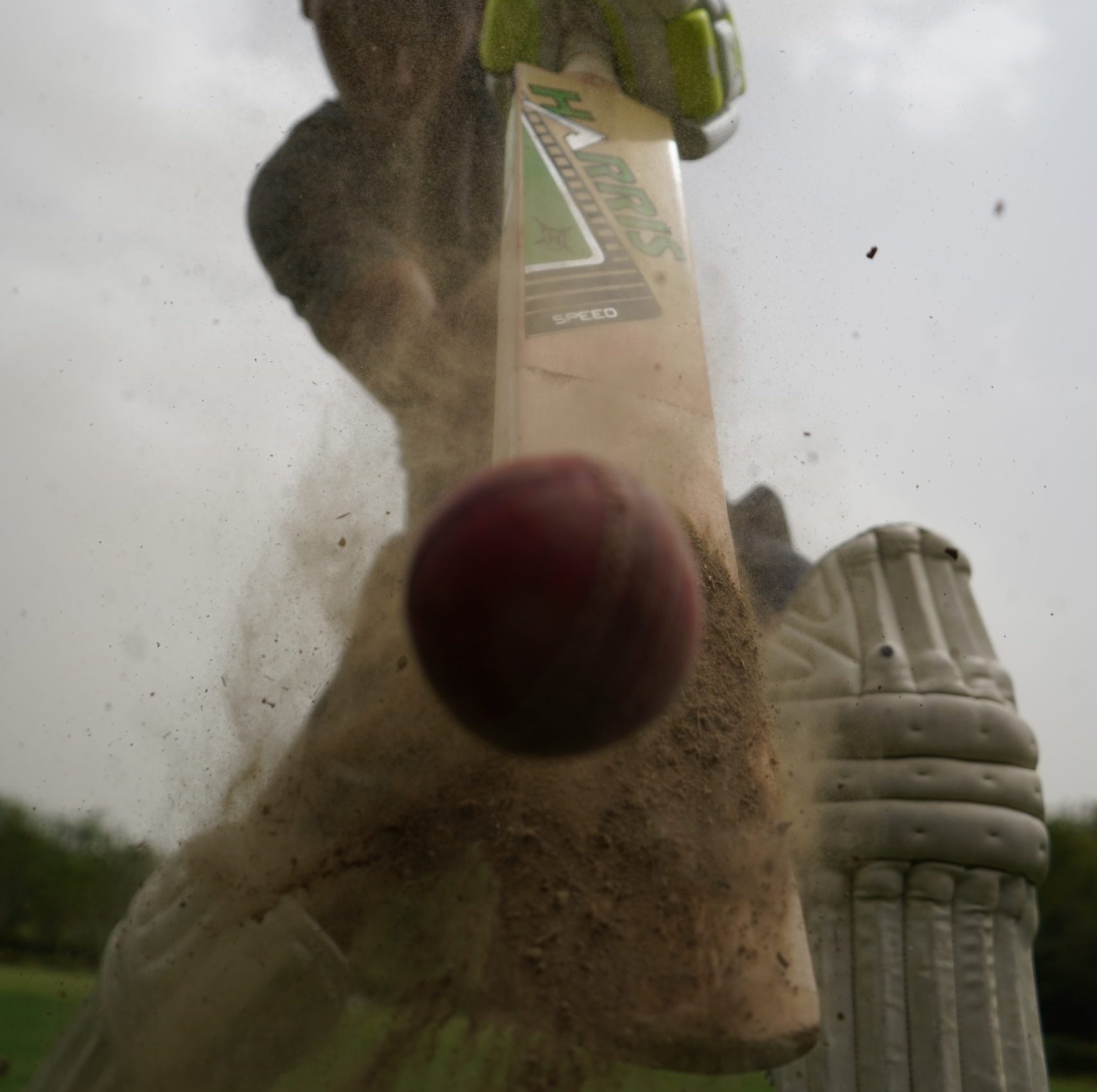 a close-up of a cricket player hitting a ball with a bat