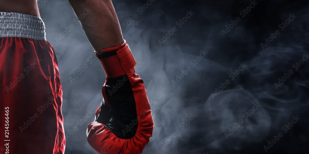 a close-up of a boxing glove on a person's hand. They are standing with their hand at their side. Their shorts are also just off to the left, mostly beyond the frame.